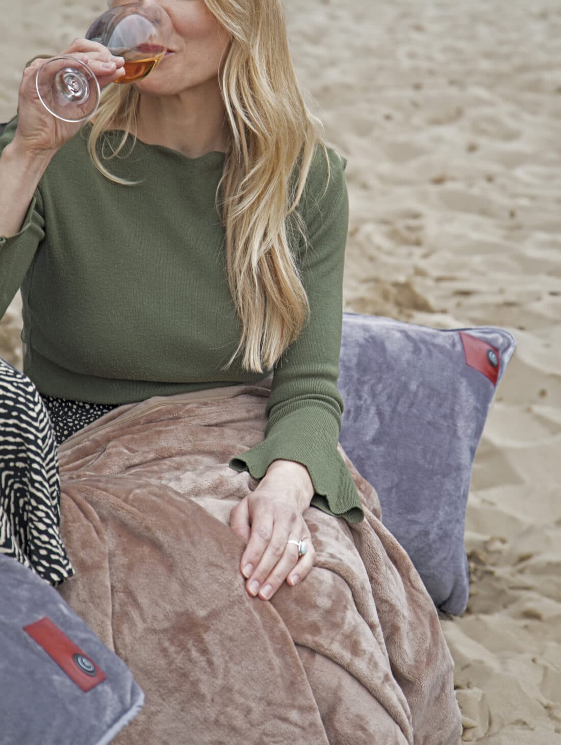 Une dame profite de la couverture chauffante infrarouge et de l'oreiller chauffant sur la plage.