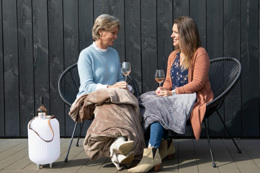 dames drinken rose in de tuin in het voorjaar en hebben een fijne infrarood warmtedeken over zich heen